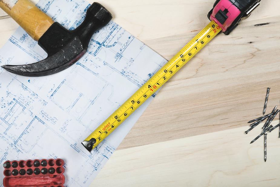 Hammer, nails and tape measure on top of a blue print.